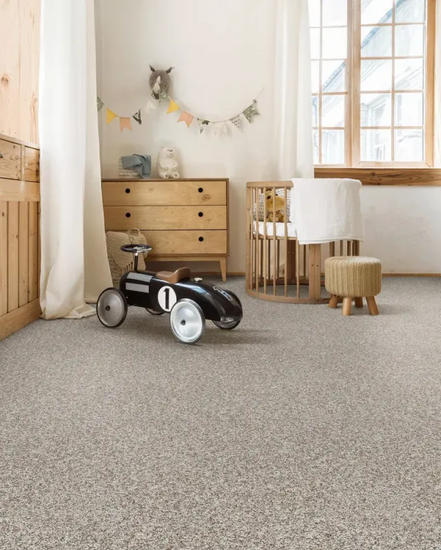 Nursery with a crib and soft neutral carpet.
