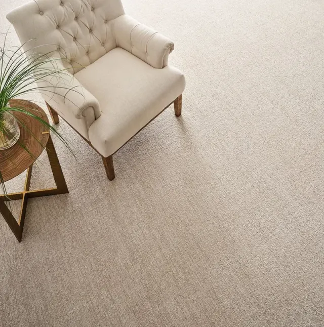 Overhead view of a tufted armchair on plush neutral carpet.
