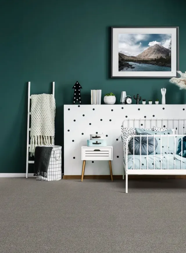 Teal kids bedroom with a crib and soft carpet.