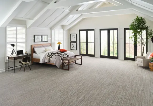 Vaulted-ceiling bedroom with French doors and patterned carpet.