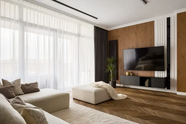 Living room with a wood accent wall and herringbone wood flooring.