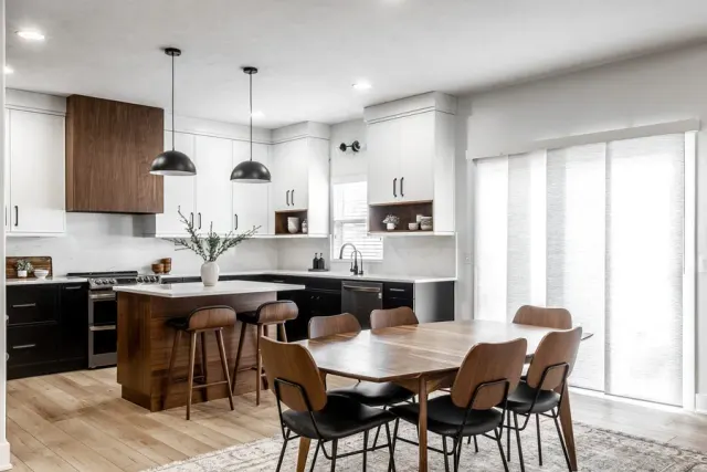 Contemporary kitchen and dining space with white and walnut cabinetry and light wood flooring.
